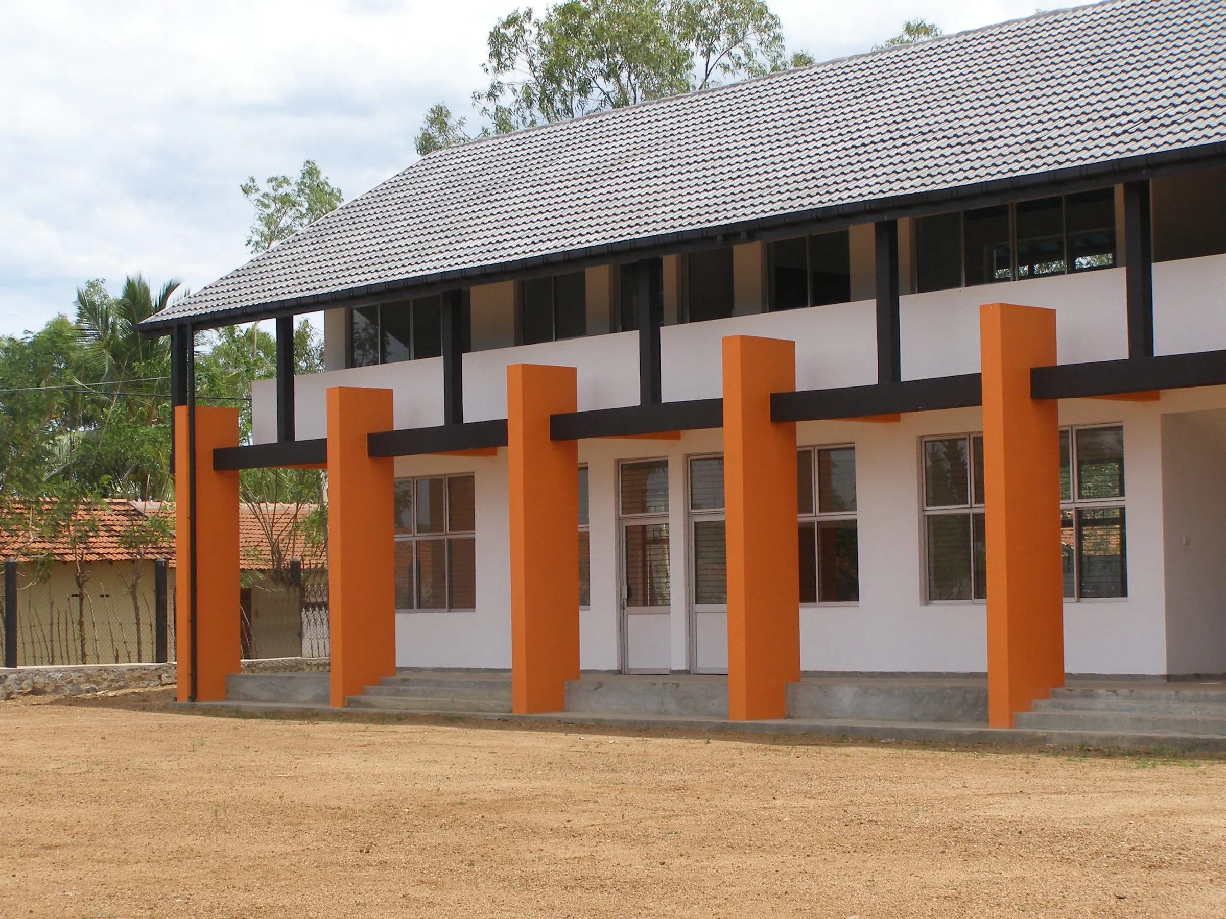 A two-storey block with orange columns, white walls and a dark tiled roof.