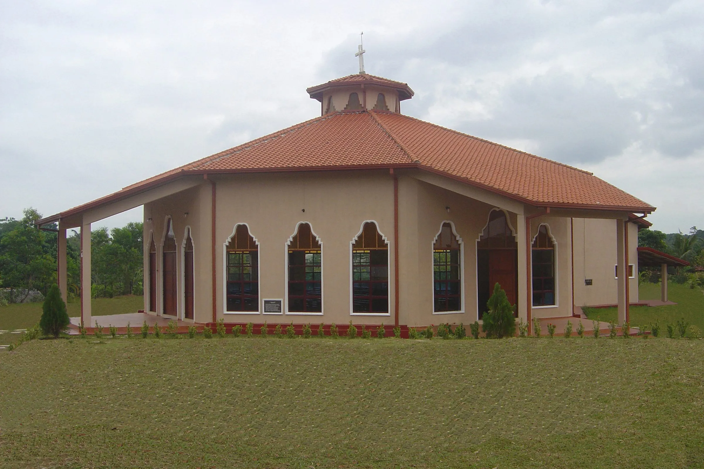 An octagonal church with a tiled roof, arched windows and a lantern at the peak.
