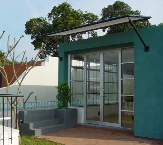 A teal-walled garden room with glazed doors and a canopy.