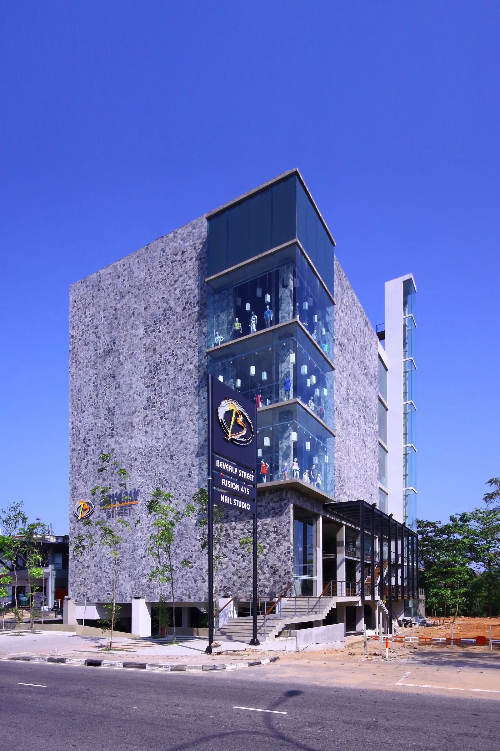 The corner of the building, with full-height glazed bays, seen from the street under a deep blue sky.