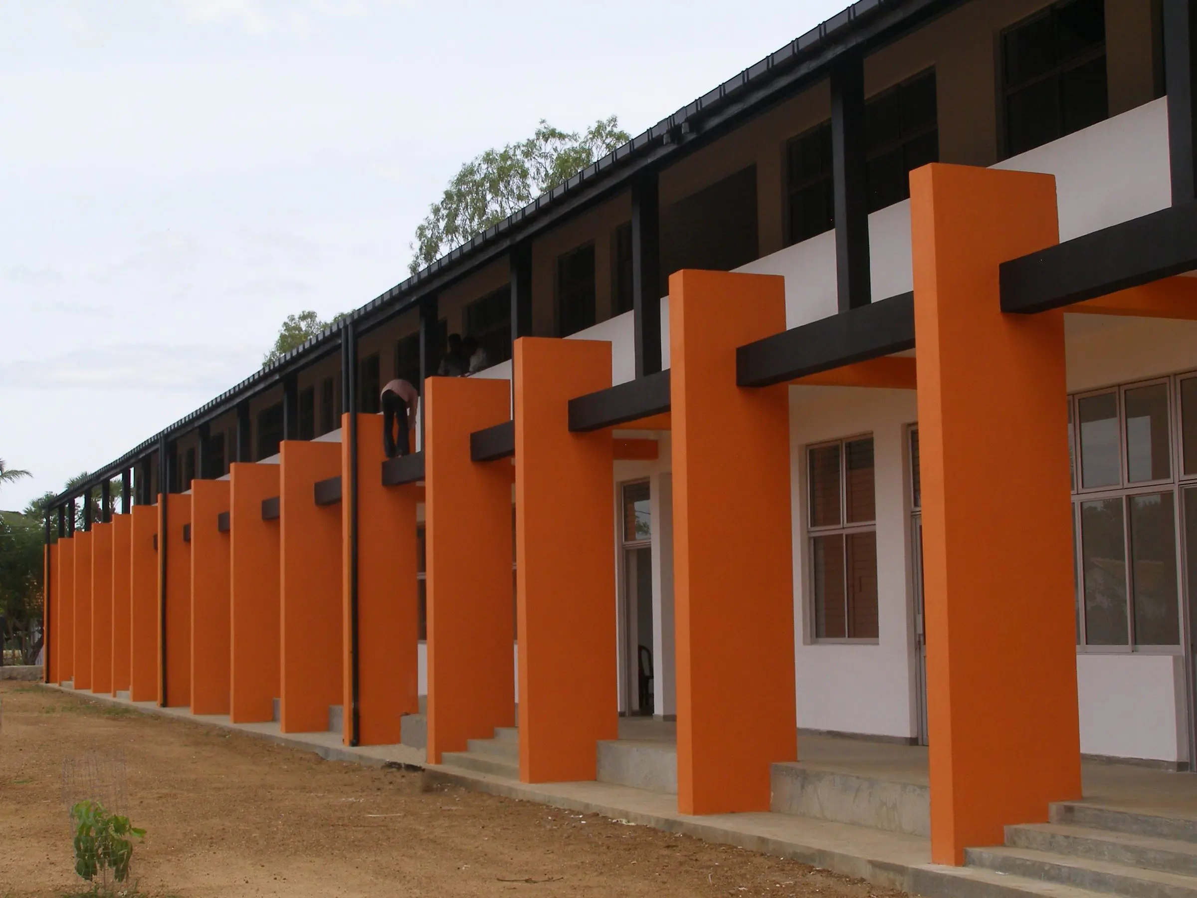 A long colonnade of orange columns along a white two-storey block.
