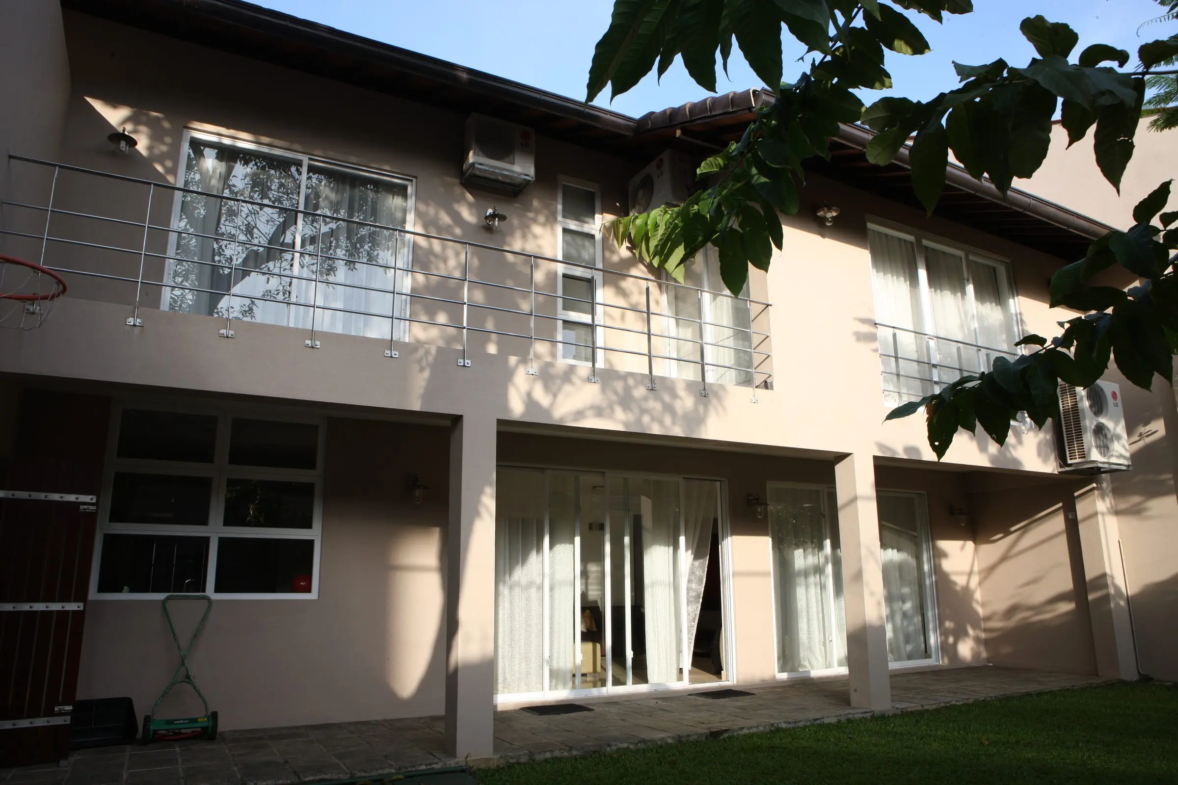 The garden elevation, with balcony railings and sliding glazing above a lawn.