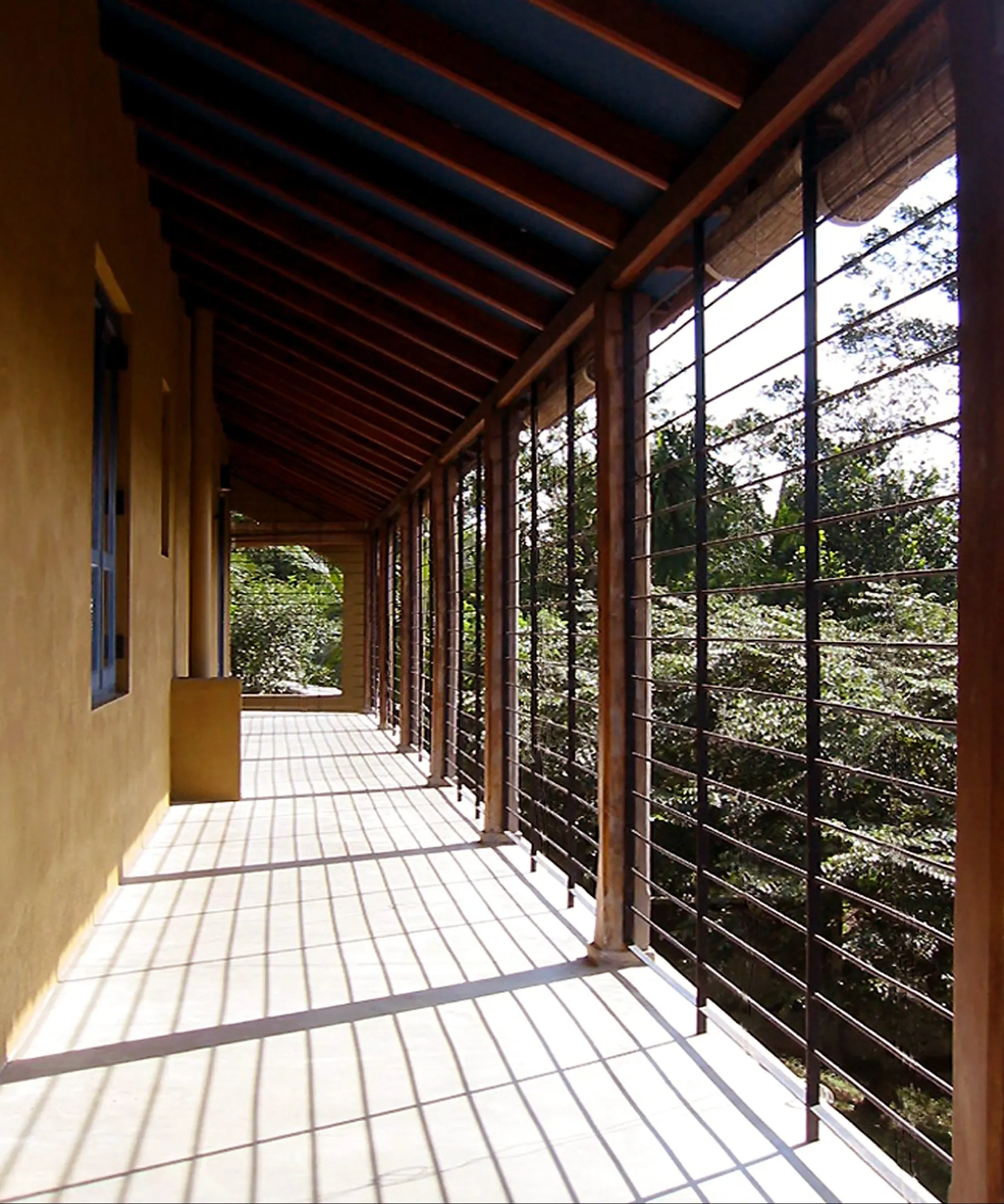 An upper veranda with horizontal bars and a floor striped with sunlight.