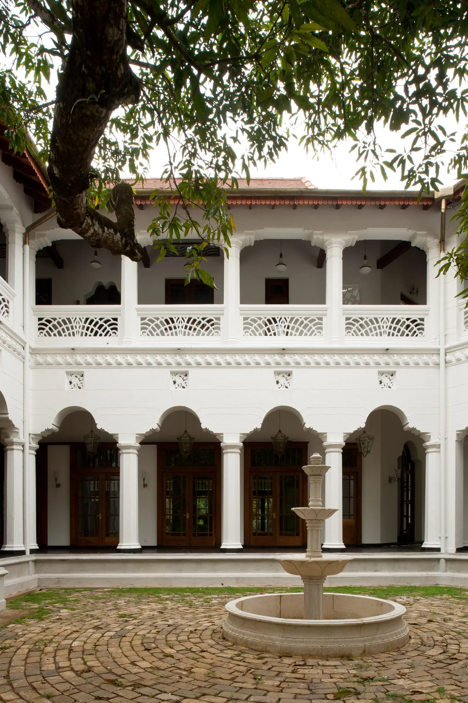 A courtyard with a fountain, an arcaded ground floor and a pierced balustrade above.