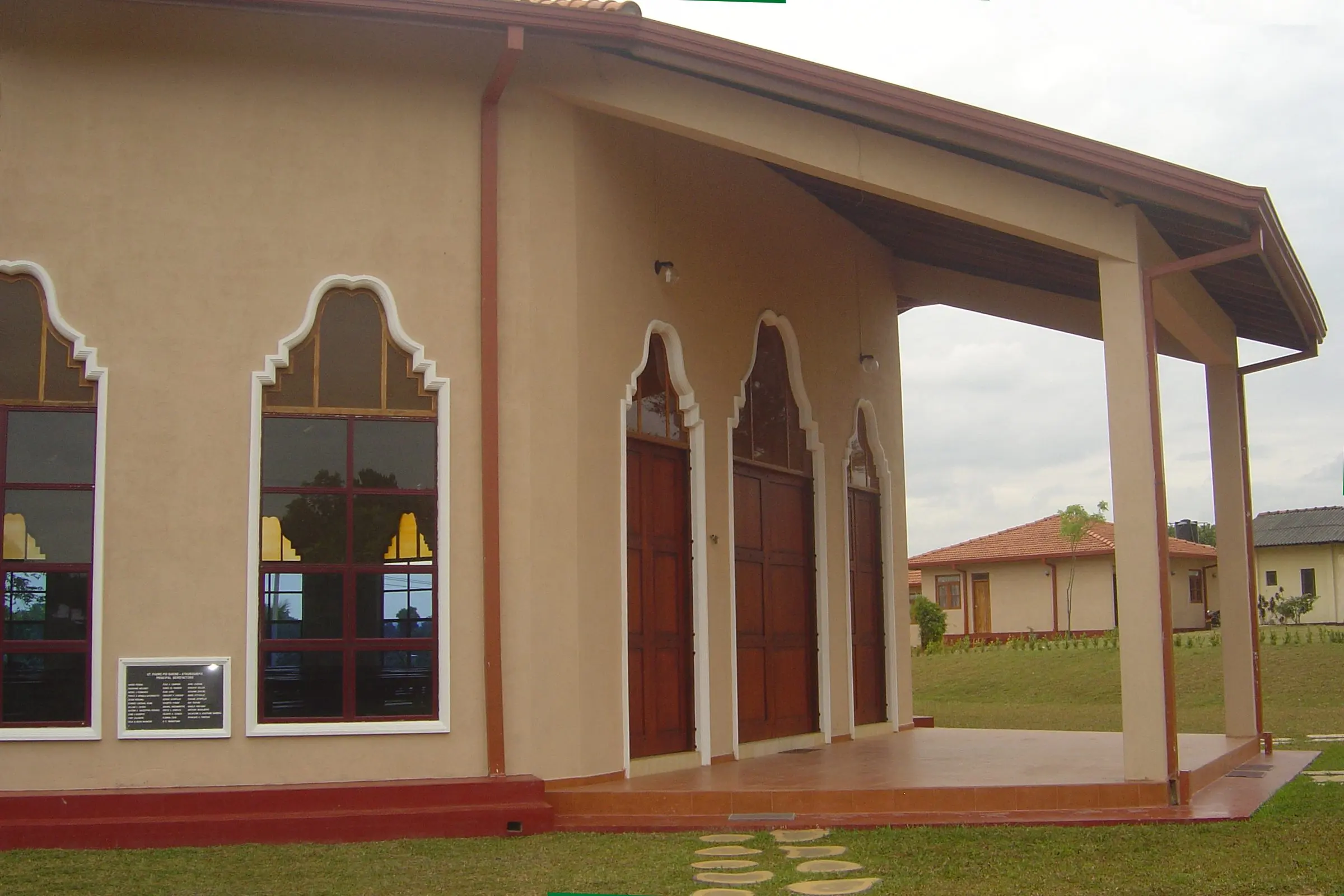 The covered porch along the church wall, with arched windows and tall doors.