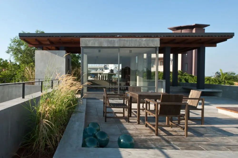 The roof pavilion by day, with a dining set and planting in the foreground.