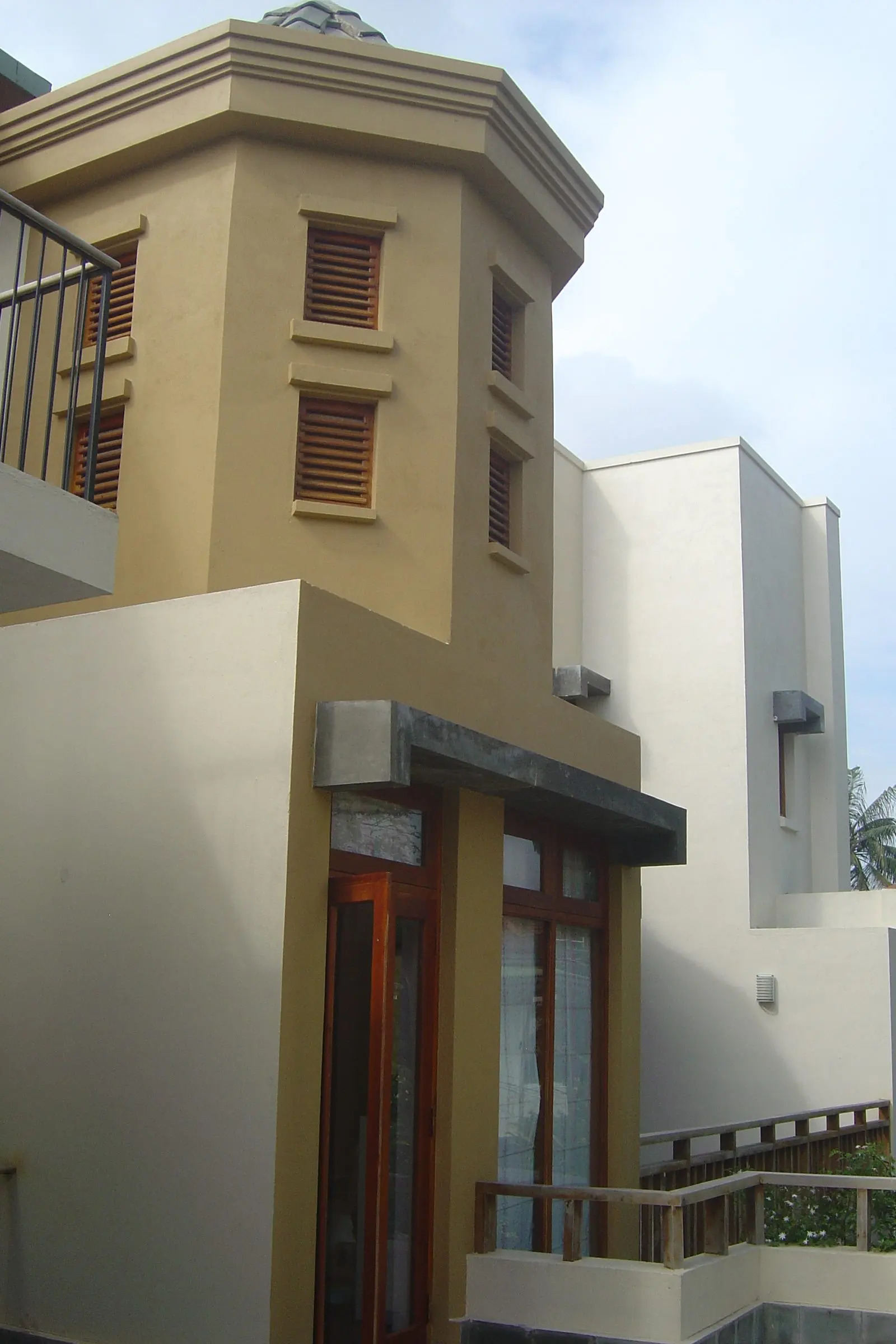 A turreted corner with louvred openings, cream walls and a balcony.
