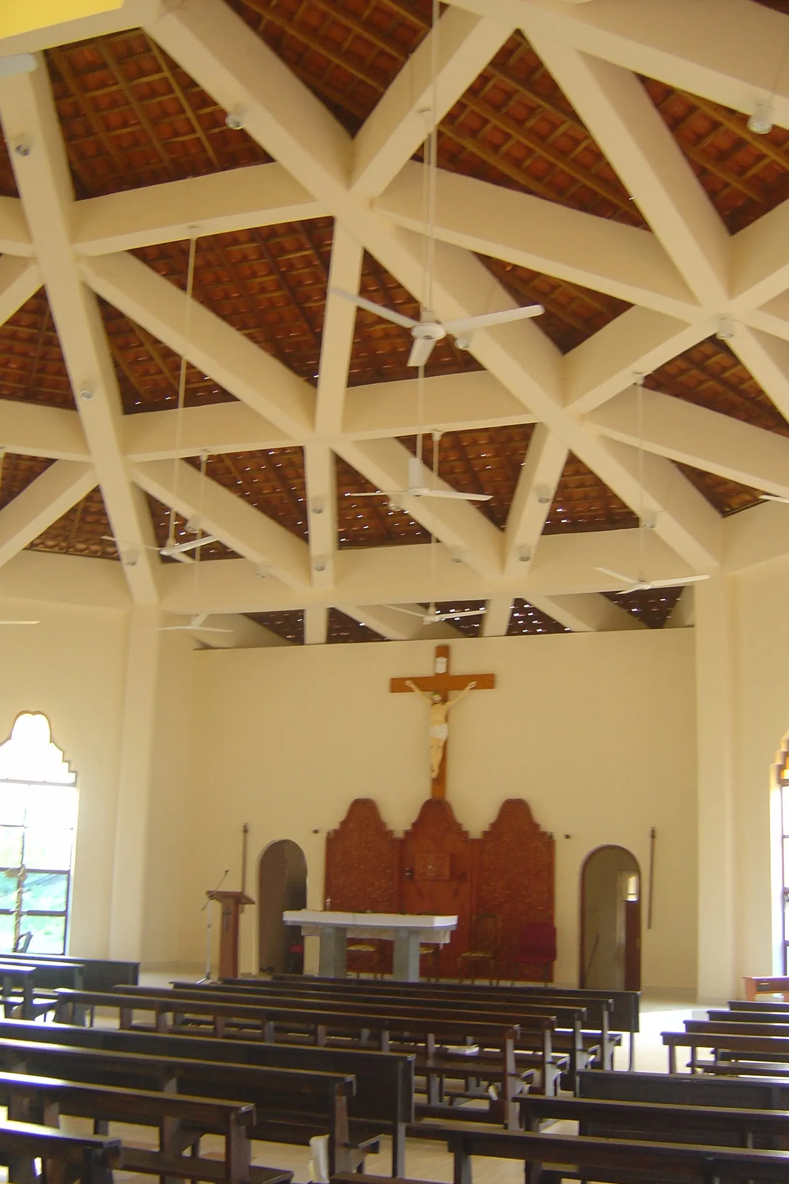 The interior: white beams radiating across the ceiling above rows of pews and the altar.