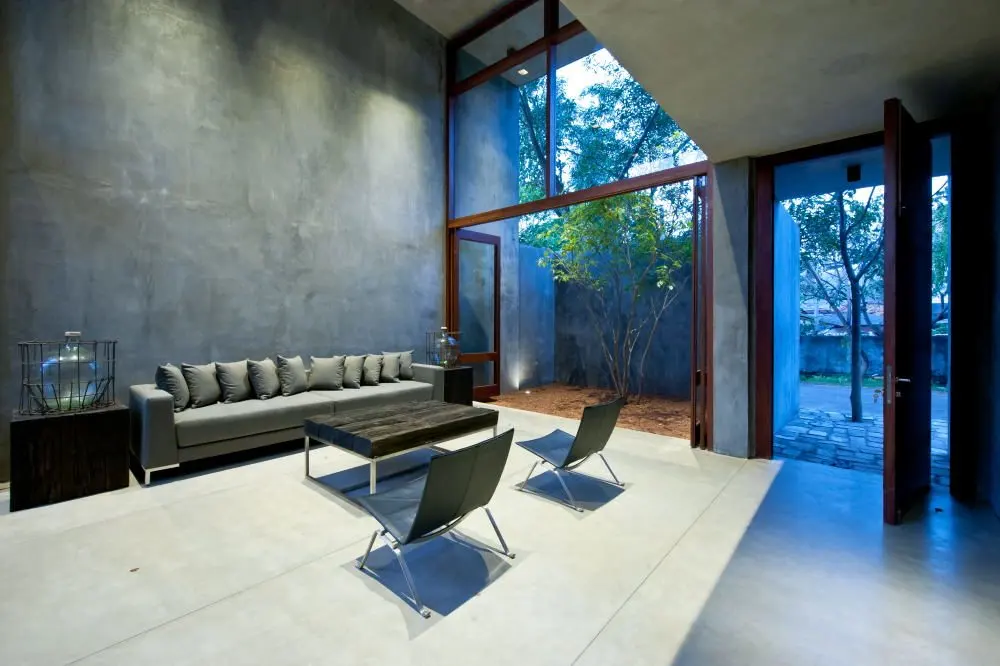 A double-height living room with a grey sofa and full-height glazing to the garden.