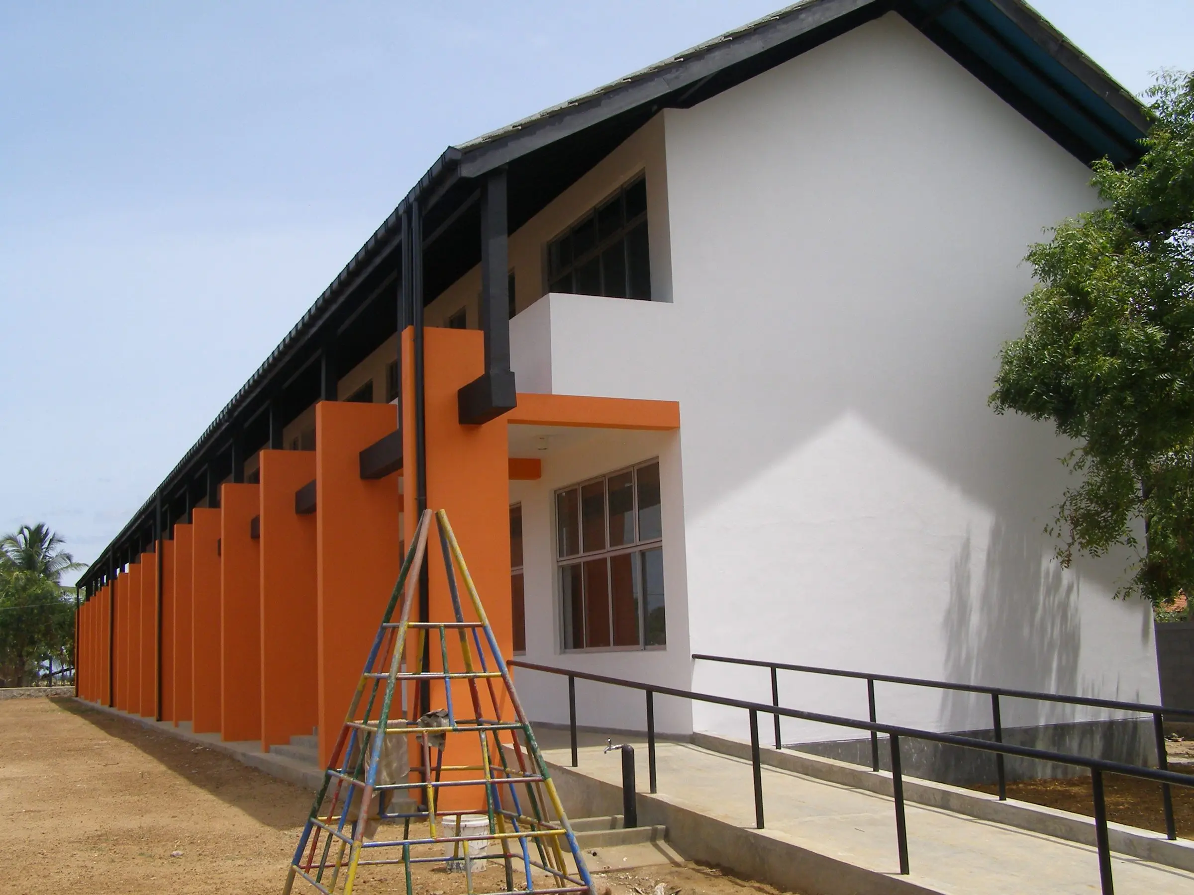 The end of the block: white walls, orange columns and a ramp with black railings.