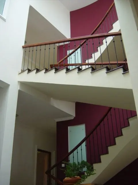A curved stair rising past a red wall.