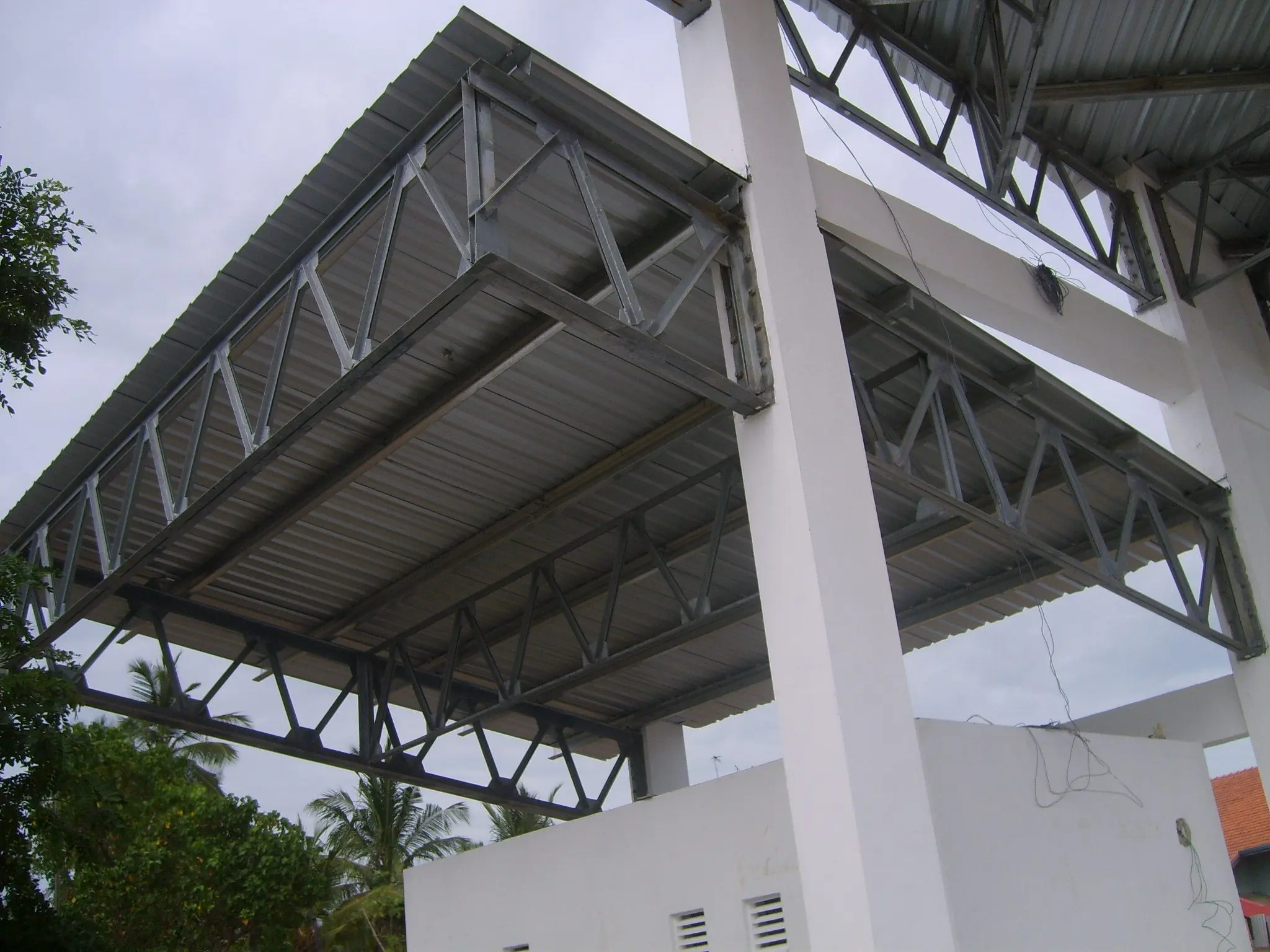 The underside of the pavilion roof beside a white pier.