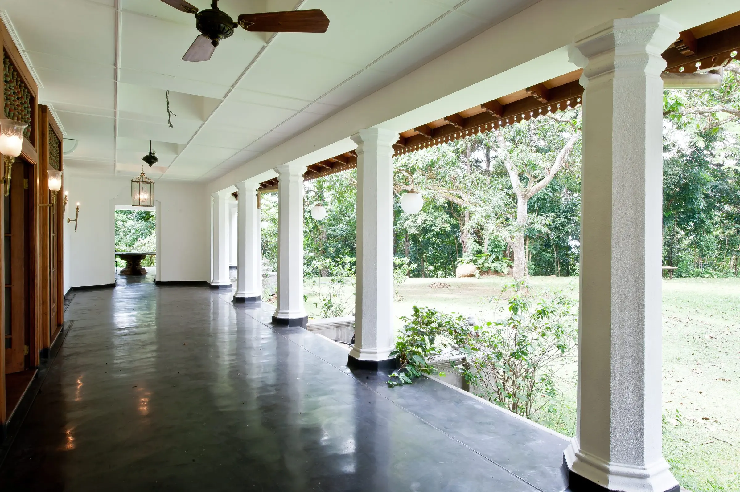 A long veranda with white columns and a black floor.
