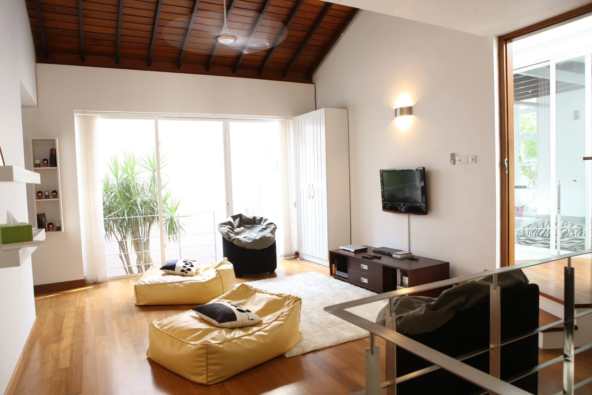 An upper lounge with a pitched ceiling, bean bags and a glazed balustrade.